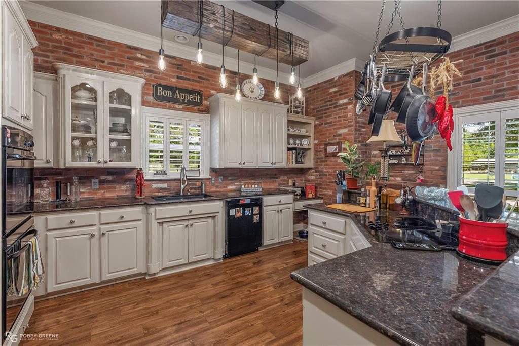 1171 Wemple Road Bossier City, LA 71111 - Photo 9 of 31 Kitchen with brick wall, crown molding, open shelves, dark stone countertops, and dark wood-style floors