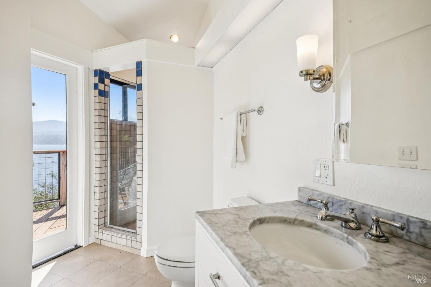17523 Highway 1 Marshall, CA 94940 - Photo 24 of 72 a bathroom with a granite countertop sink a mirror and shower