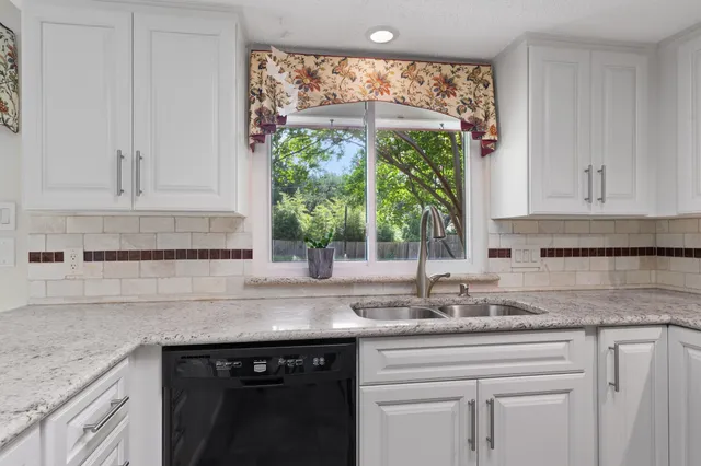 a kitchen with granite countertop white cabinets and a large window