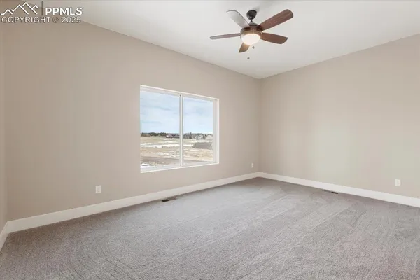 an empty room with windows and fan