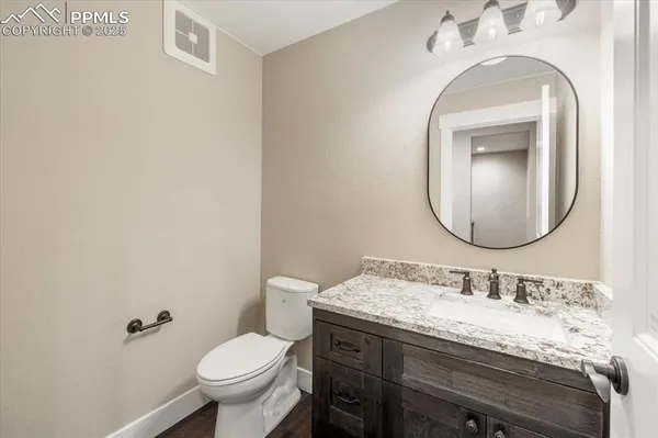 a bathroom with a granite countertop toilet a sink and mirror