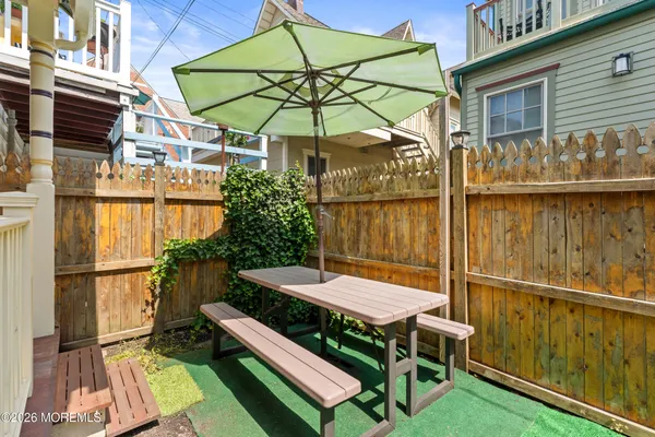 a view of a roof deck with table and chairs with wooden floor and fence