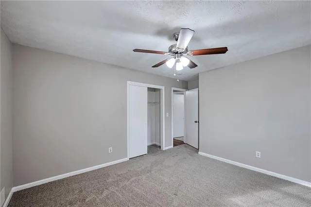 an empty room with a ceiling fan and a window