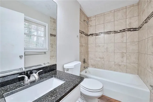 a bathroom with a granite countertop sink toilet a mirror and shower