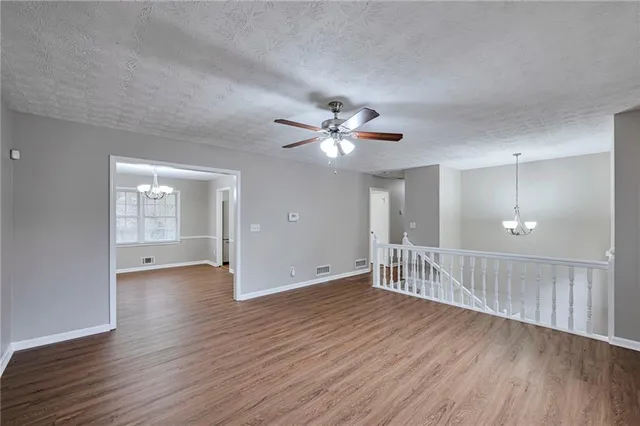 a view of an empty room with wooden floor and a ceiling fan