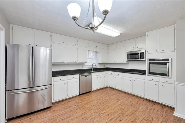 a kitchen with granite countertop white cabinets and stainless steel appliances