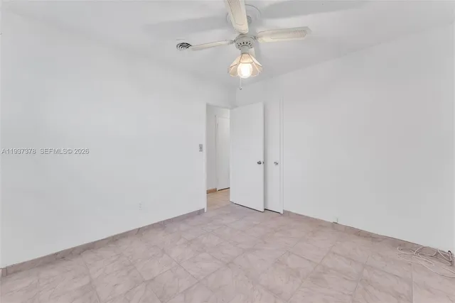 an empty room with a chandelier fan and closet area