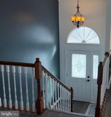 a view of staircase with railing and a chandelier