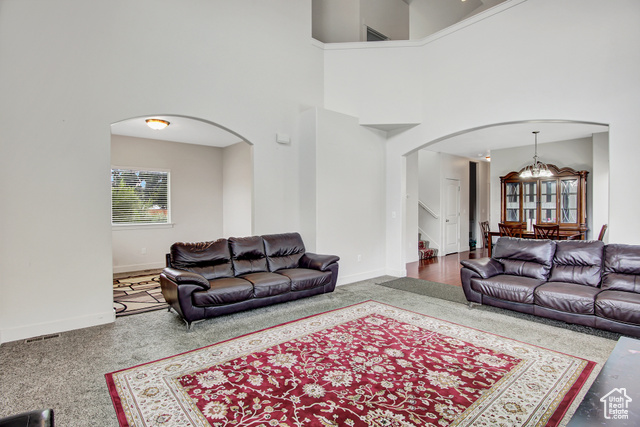 4 Hanauer Place Murray, UT 84107 - Photo 6 of 24 Carpeted living room featuring arched walkways, a chandelier, a towering ceiling, and stairs