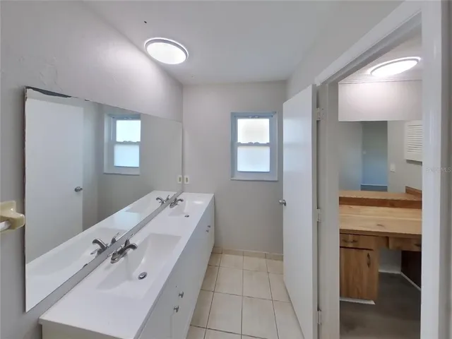 a spacious bathroom with a double vanity sink a mirror and a bathtub