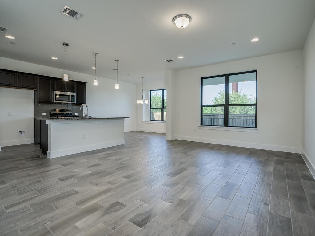 12327 Maypole Bend Austin, TX 78717 - Photo 5 of 30 an empty room with wooden floor and a kitchen