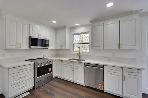 a kitchen with white cabinets stainless steel appliances and sink