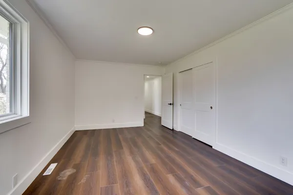 a view of wooden floor in an empty room with a window