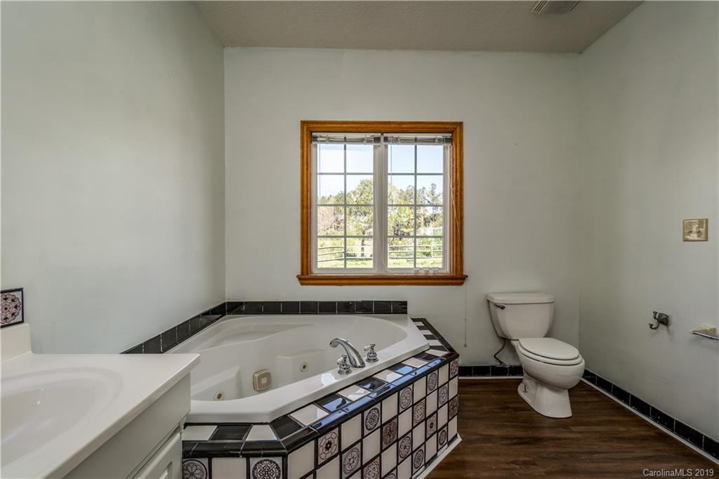 4501 Rowell Road Lancaster, SC 29720 - Photo 19 of 39 a bathroom with a granite countertop bathtub a toilet and a window