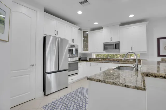 a kitchen with granite countertop white cabinets and stainless steel appliances