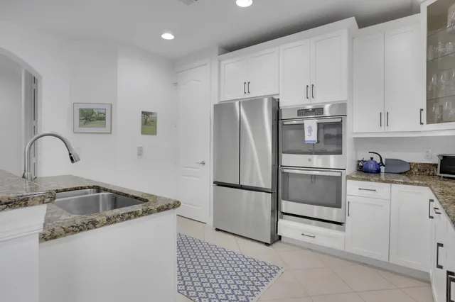 a kitchen with granite countertop white cabinets sink and stainless steel appliances