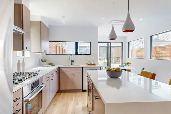 a kitchen with stainless steel appliances a stove a sink dishwasher a dining table and chairs with wooden floor