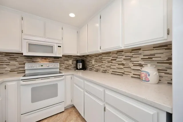 a kitchen with white cabinets and white appliances