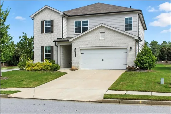 a view of a white house next to a yard and large trees