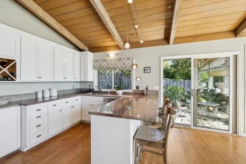 a large kitchen with granite countertop a large window and white cabinets