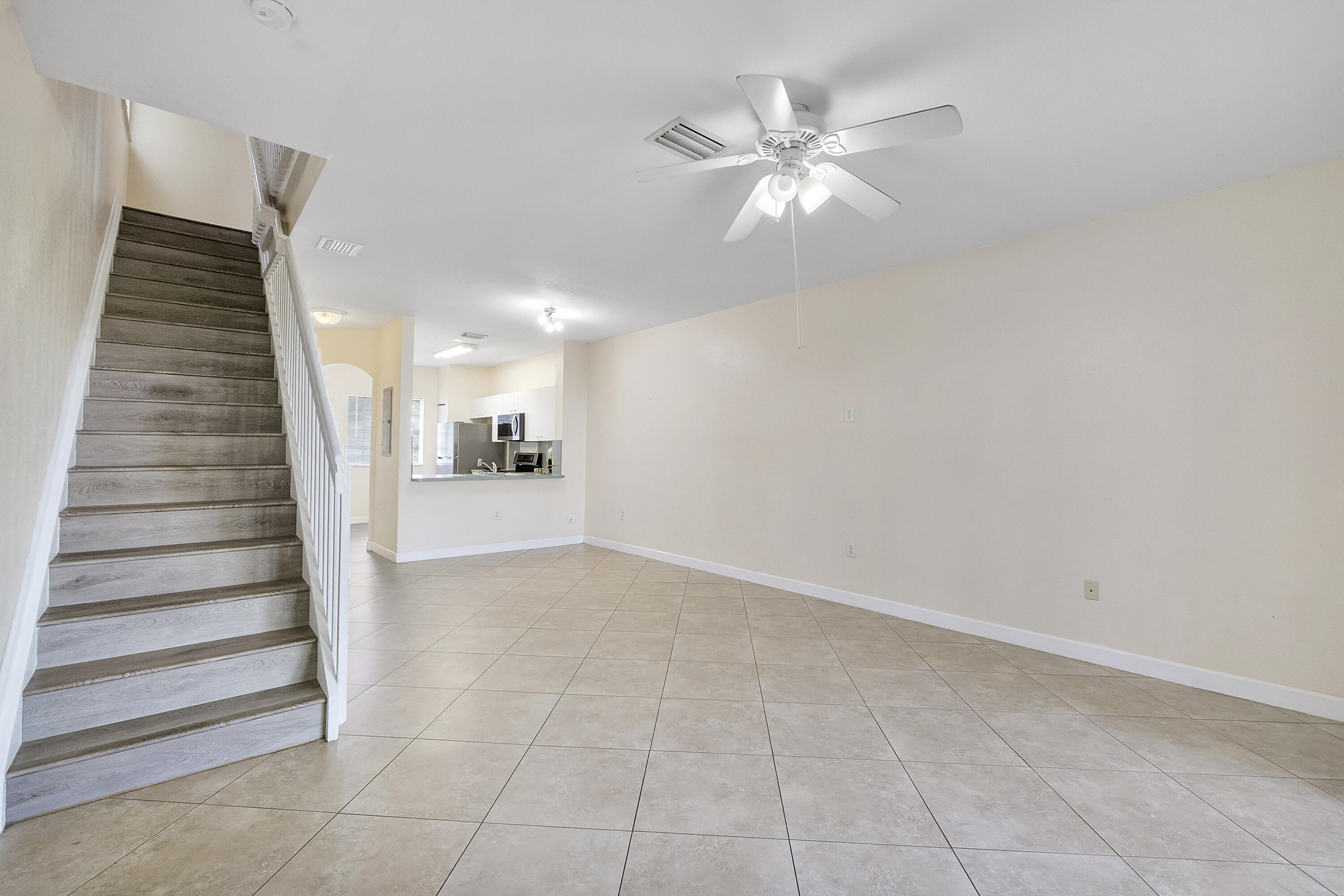 5910 Riverside Avenue Tamarac, FL 33321 - Photo 17 of 47 a view of an empty room with stairs and a chandelier fan