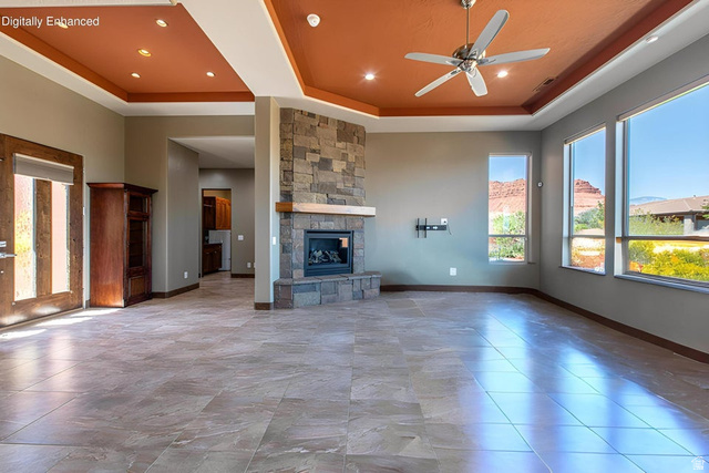 322 340 E Street Ivins, UT 84738 - Photo 7 of 61 Spacious living area featuring large format tile flooring, a stone fireplace with a wood mantle, a tray ceiling with recessed lighting and a ceiling fan, and multiple large windows
