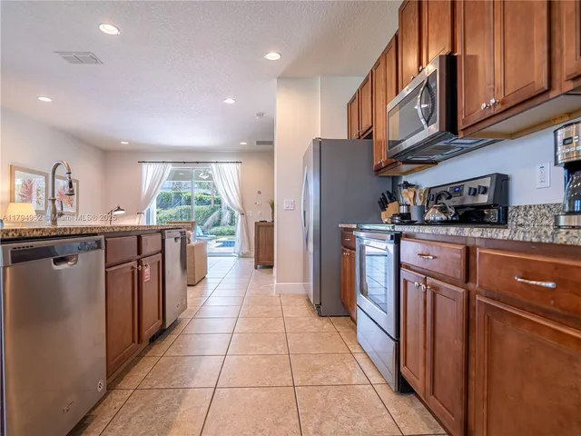 a kitchen with stainless steel appliances granite countertop a refrigerator a sink a stove top oven and cabinets