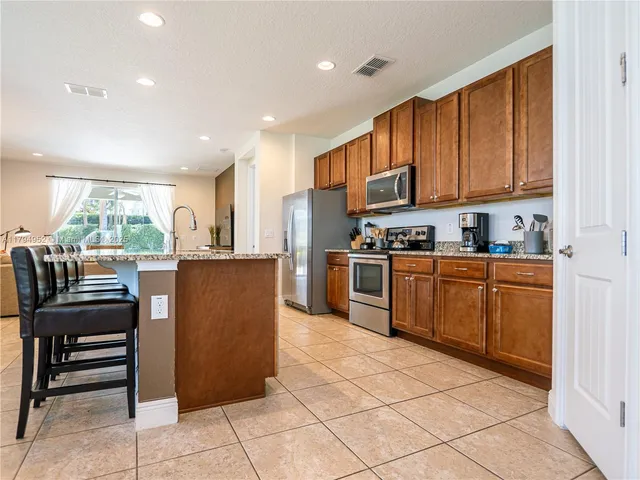 a kitchen with stainless steel appliances granite countertop a refrigerator top oven and a view of living room