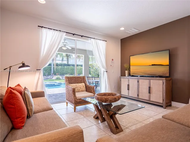 a living room with furniture a flat screen tv and floor to ceiling window