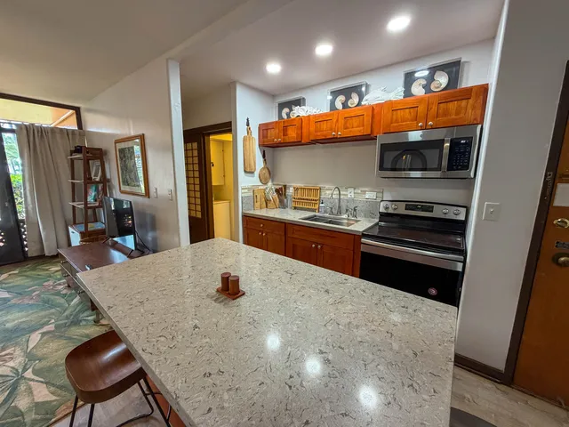 a kitchen with stainless steel appliances a stove a refrigerator a sink a dining table and chairs