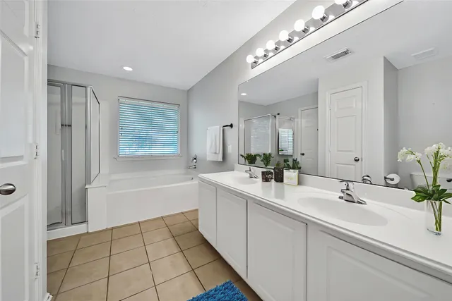 a spacious bathroom with a double vanity sink a mirror and a bathtub