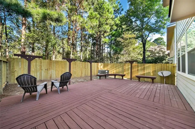 a view of a roof deck with table and chairs a barbeque with wooden floor and fence