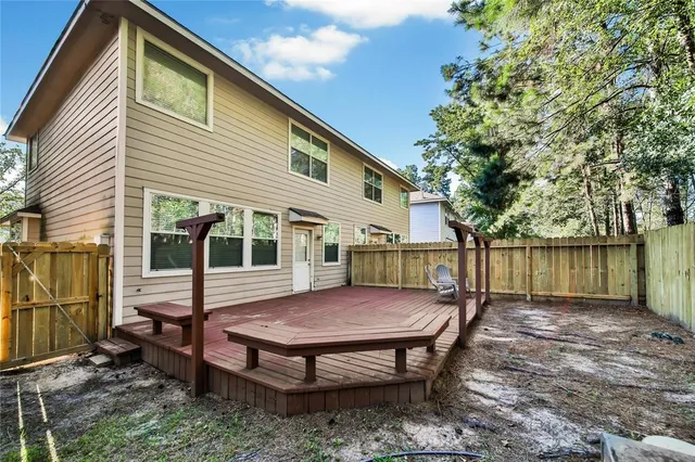 a view of backyard with a deck and wooden fence