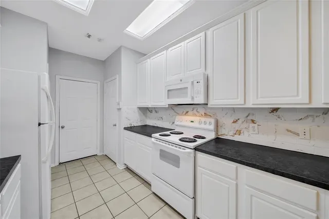 a kitchen with white cabinets and appliances