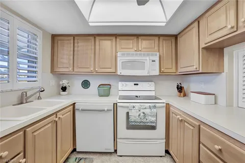 a kitchen with stainless steel appliances granite countertop white cabinets sink and window