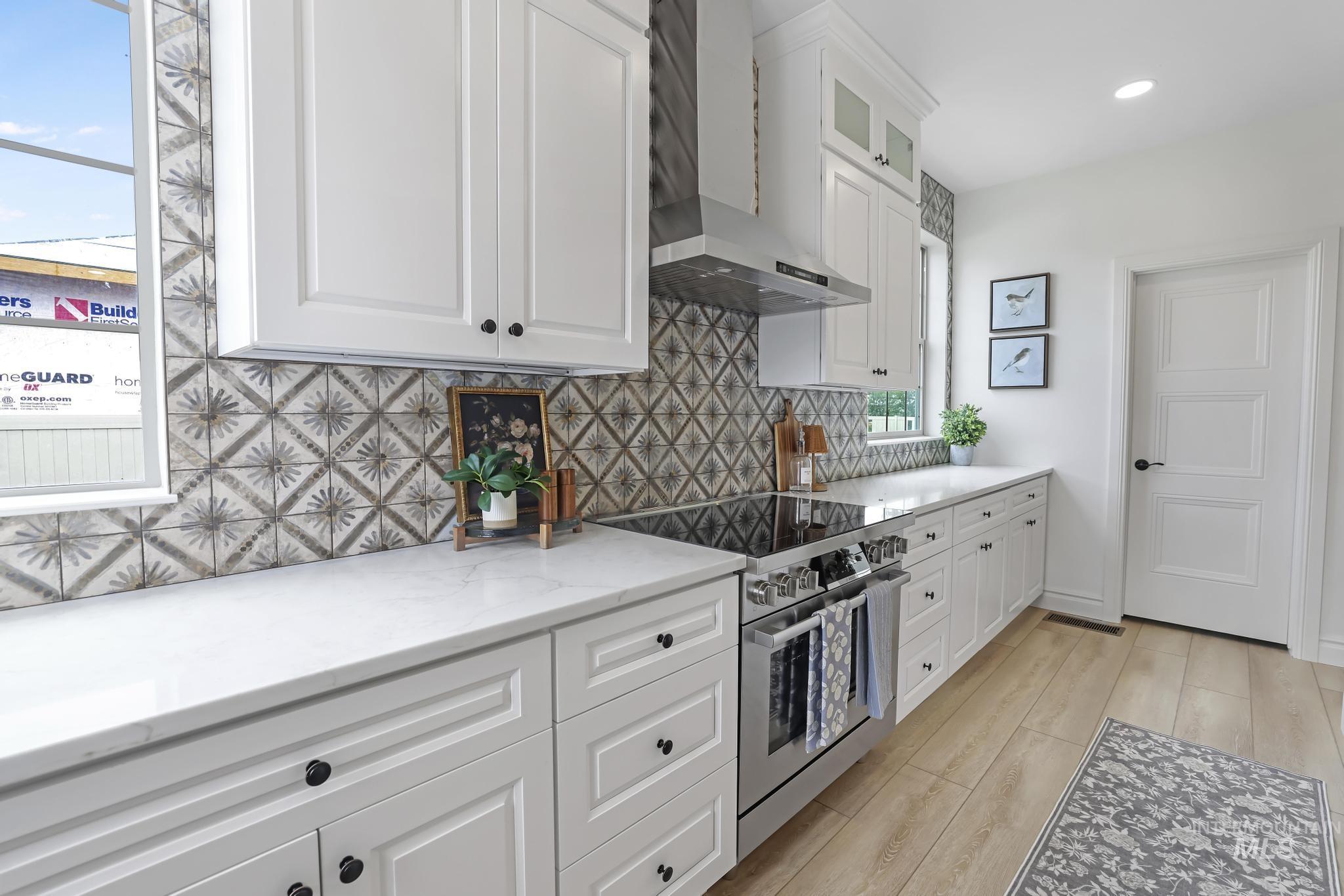 866 Quartz Road Kimberly, ID 83341 - Photo 18 of 48 Kitchen featuring white shaker-style cabinetry, patterned tile backsplash, light-toned wood-finish flooring, stainless steel range with overhead hood, and white countertops