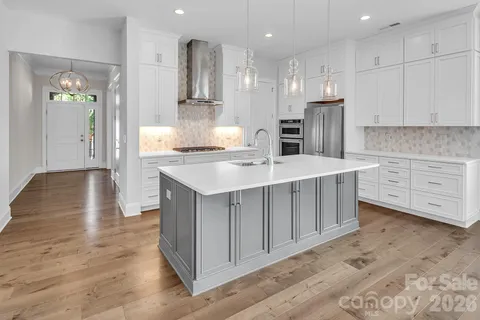 a kitchen with kitchen island white cabinets and stainless steel appliances