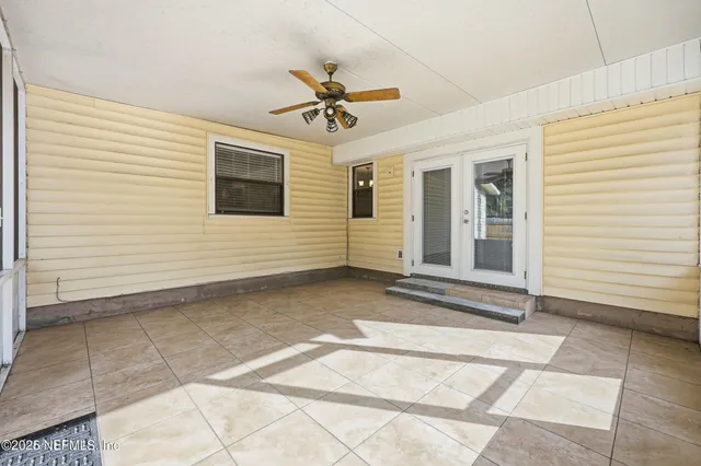 an empty room with wooden floor chandelier fan and windows