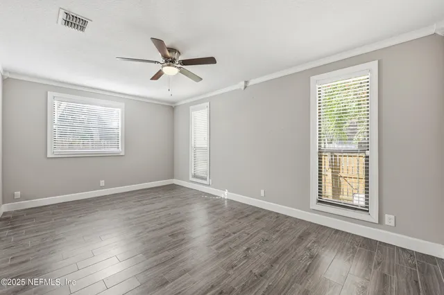 a view of a room with wooden floor and ceiling fan