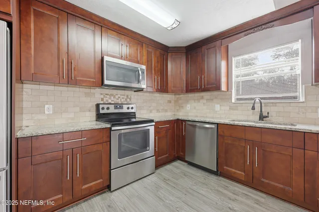 a kitchen with granite countertop wooden floors stainless steel appliances and cabinets