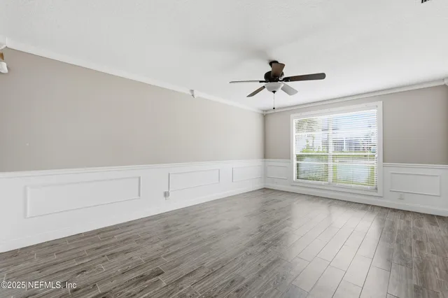 an empty room with wooden floor and ceiling fan