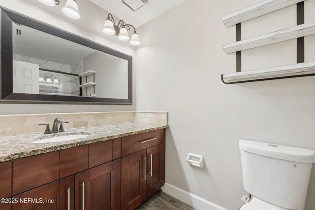 a bathroom with a granite countertop sink a toilet and a mirror