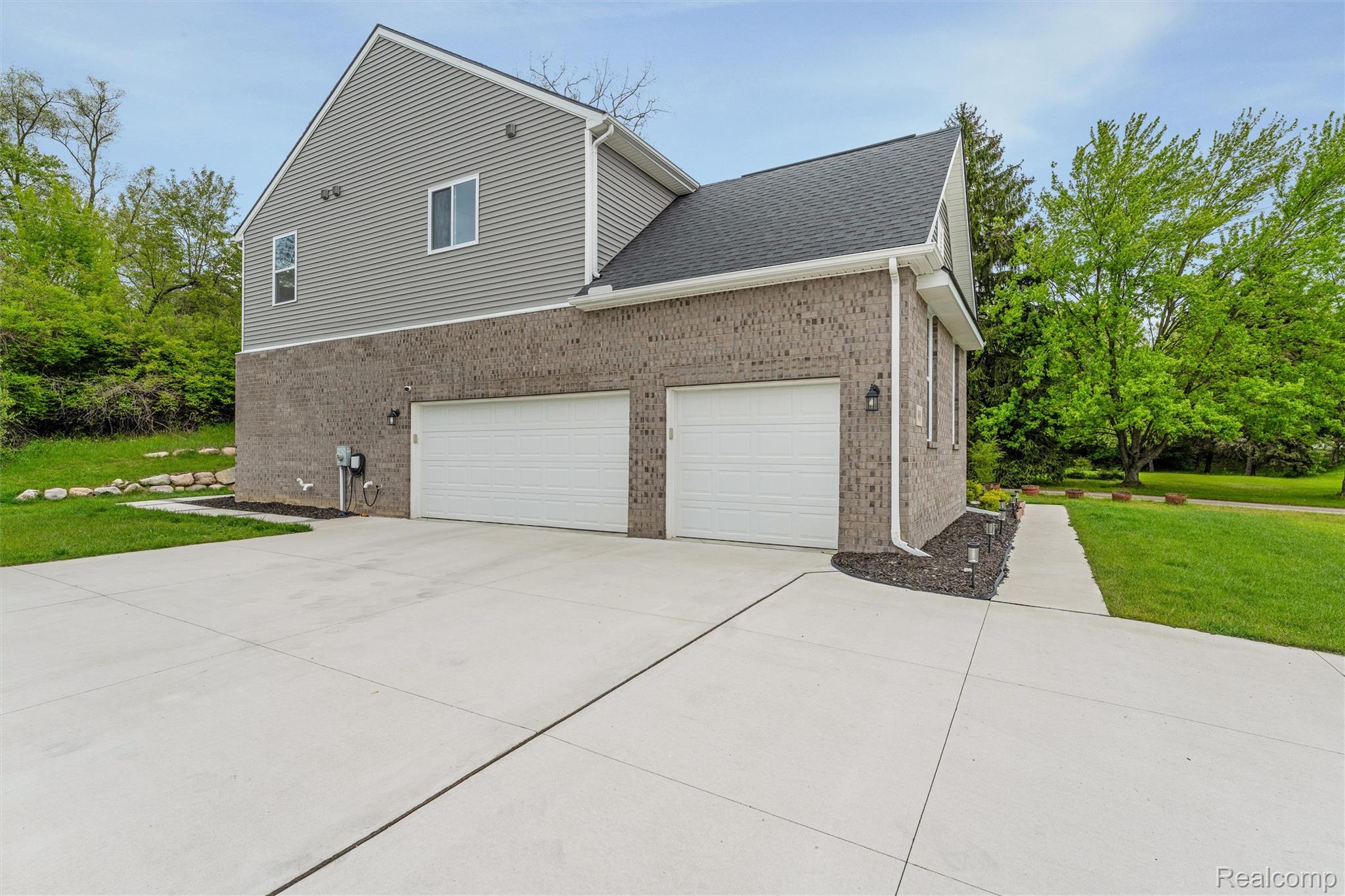 908 South Livernois Road Rochester, MI 48309 - Photo 44 of 49 View of side of property with a yard, concrete driveway, brick siding, a shingled roof, and a garage