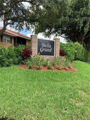 a view of a sign in front of a house with a tree