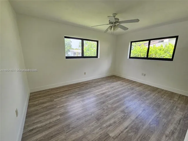 a view of an empty room with a window and wooden floor