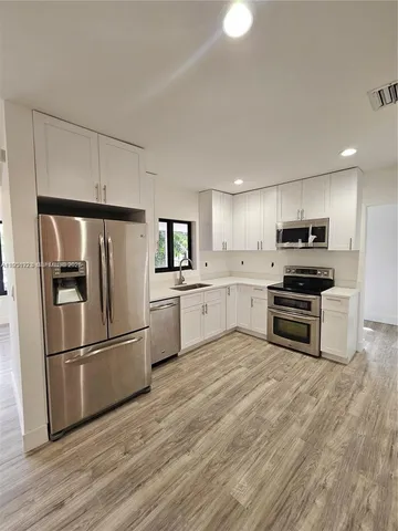 a kitchen with granite countertop a refrigerator and a stove top oven