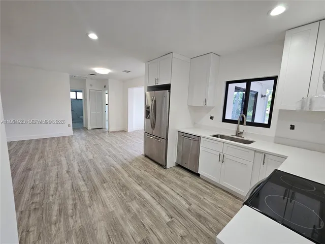 a large kitchen with a wooden floor and white cabinets
