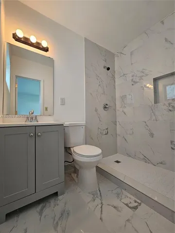 a bathroom with a toilet a sink a mirror and shower