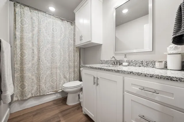 a bathroom with a granite countertop toilet a sink and a mirror