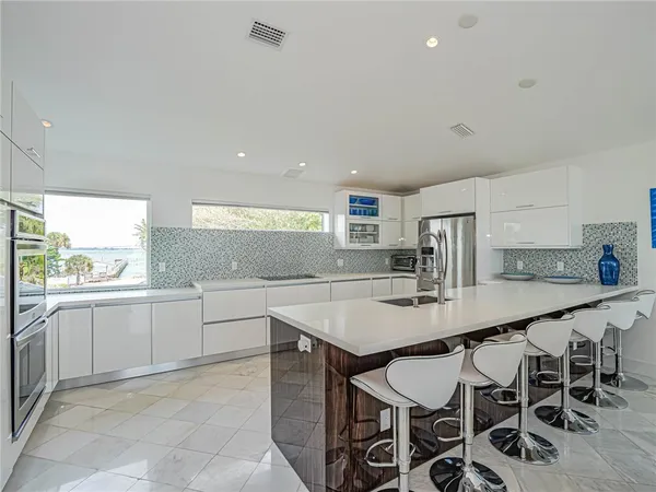 a kitchen with stainless steel appliances granite countertop a table chairs sink and cabinets